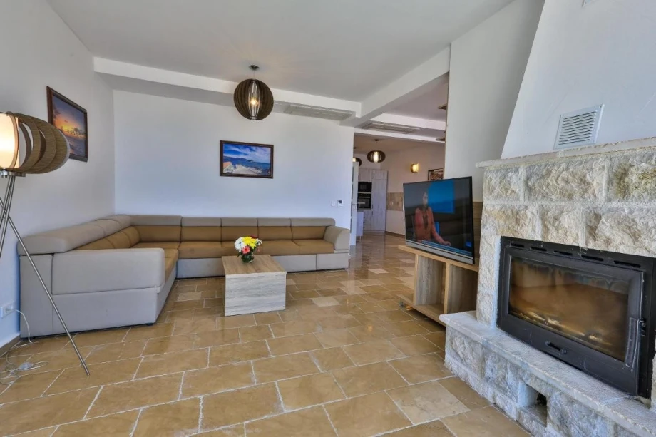 Fireplace and a corner sofa adorning the living room of in a villa for rent in Sveti Stefan