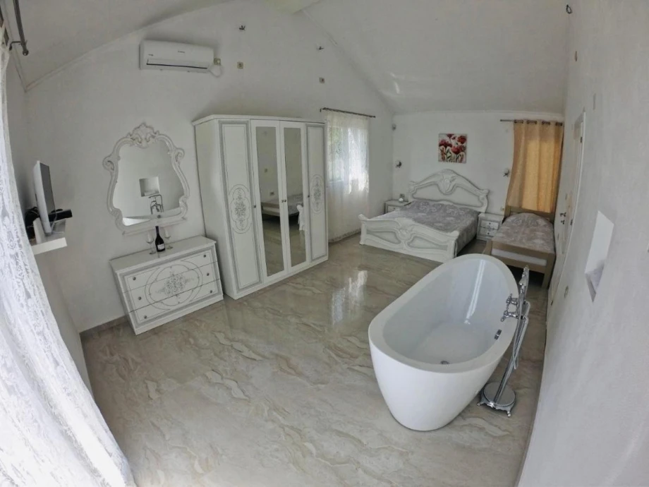 Bathtub in a luxuriously furnished room with pearly white furniture