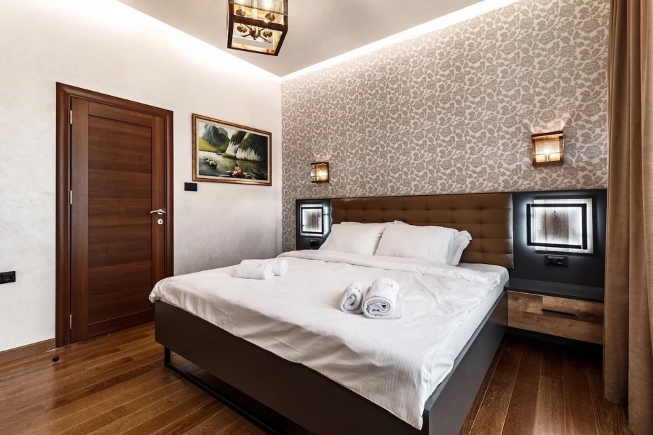 Modern bedroom for two with a large comfortable bed and wall lamps in the Victoria Residence Penthouse in Budva Montenegro