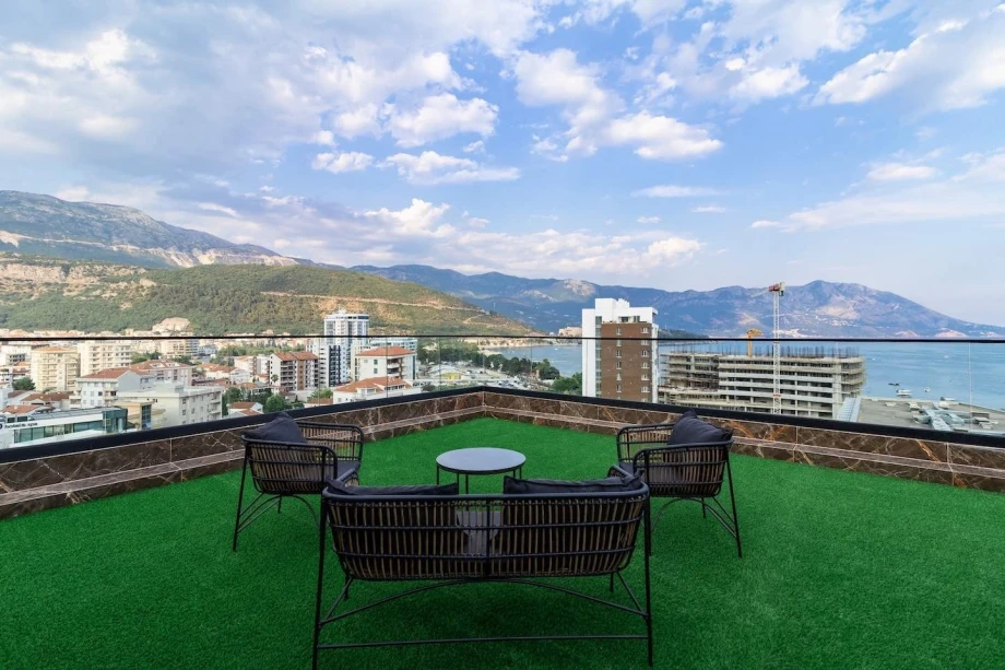 A spacious terrace with a table and chairs overlooking the sea in Victoria Residence Penthouse in Budva