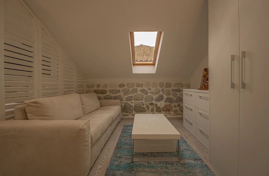 Modernly equipped room with white furniture which offers sights of the sea and the surrounding mountains