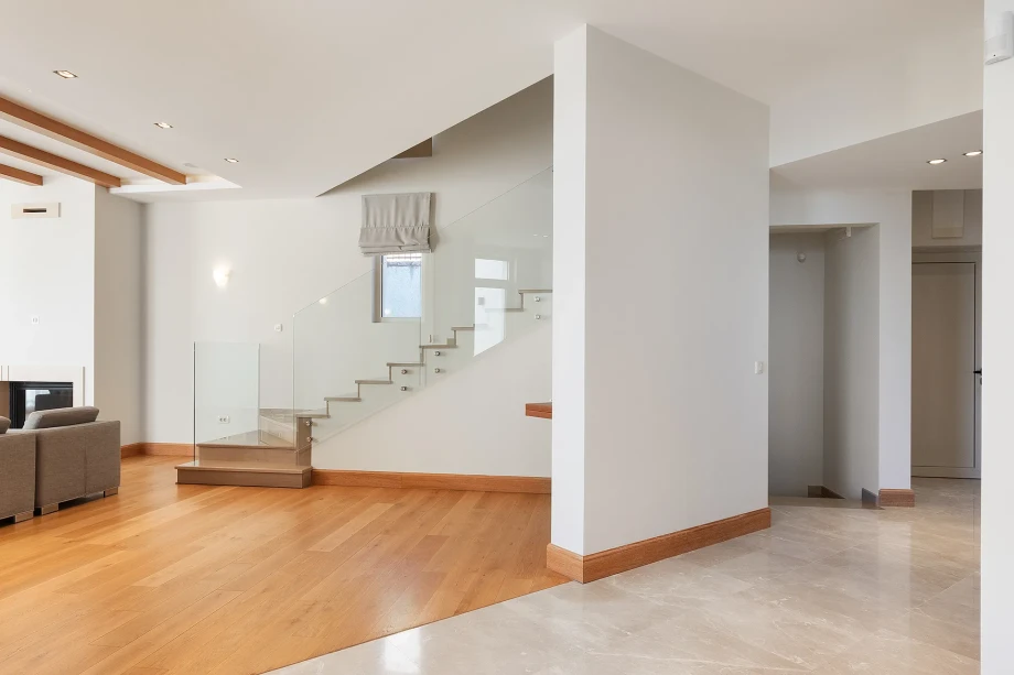 Bright modern villa interior showcasing a floating glass-railed staircase